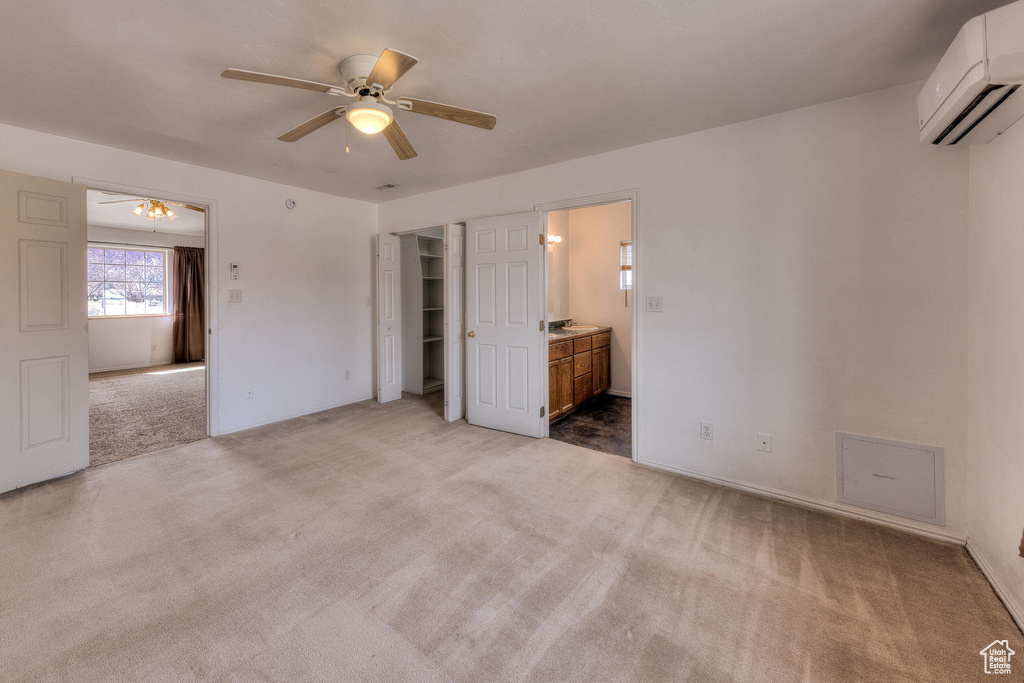 Unfurnished bedroom featuring a wall mounted air conditioner, ceiling fan, connected bathroom, and carpet