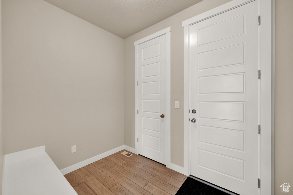 Entryway with baseboards, light wood finished floors, and visible vents