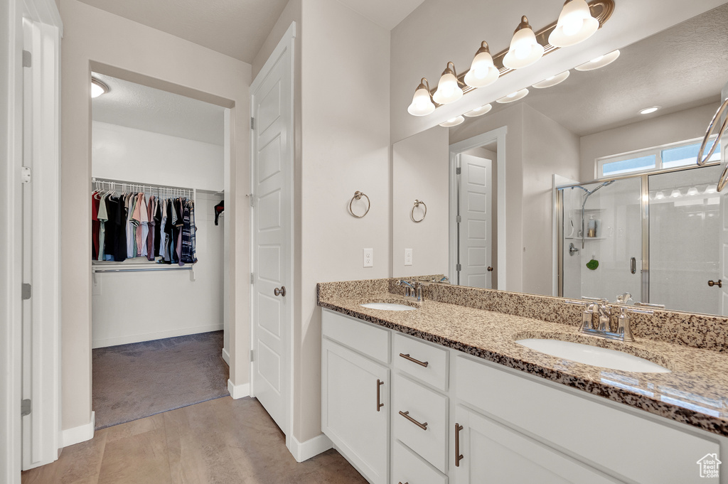 Full bath featuring double vanity, a sink, a walk in closet, and a stall shower