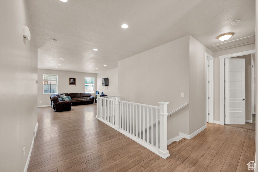 Hallway featuring baseboards, recessed lighting, wood finished floors, and an upstairs landing