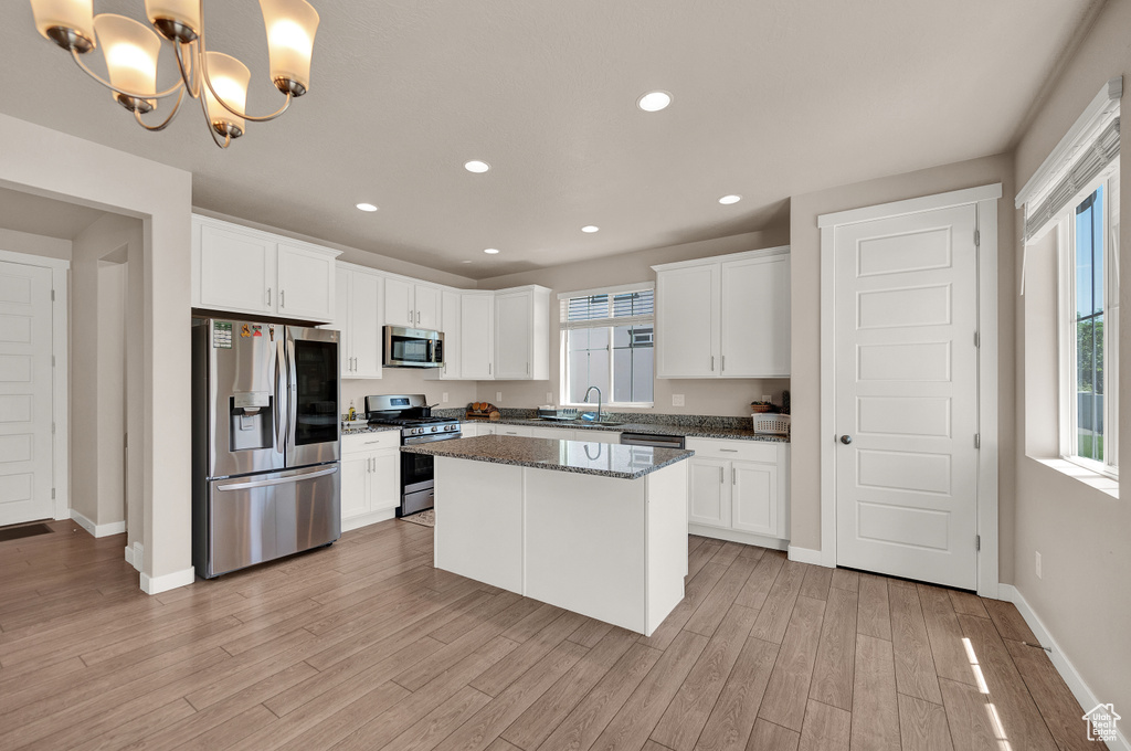 Kitchen with baseboards, white cabinetry, a sink, light wood finished floors, and appliances with stainless steel finishes