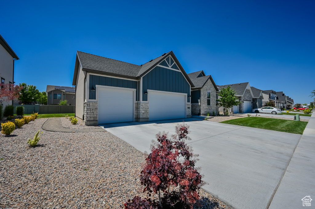 Craftsman house featuring a residential view, fence, an attached garage, board and batten siding, and driveway