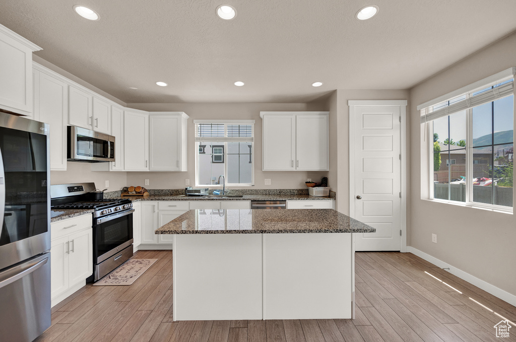 Kitchen with a sink, appliances with stainless steel finishes, baseboards, and light wood-style flooring