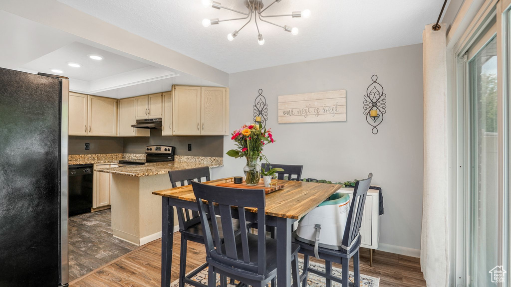 Dining area featuring wood finished floors, baseboards, a chandelier, a tray ceiling, and recessed lighting