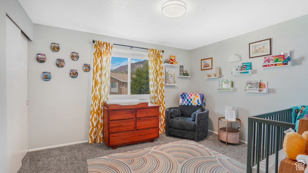 Bedroom with carpet floors, baseboards, and a crib