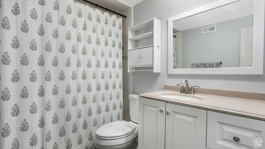 Bathroom featuring toilet, visible vents, a shower with shower curtain, and vanity