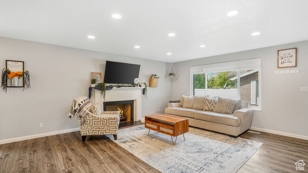Living area with baseboards, a lit fireplace, recessed lighting, and wood finished floors