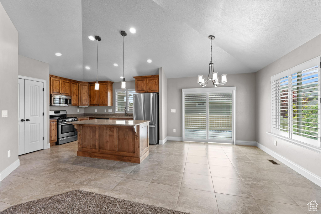 Kitchen featuring brown cabinets, appliances with stainless steel finishes, visible vents, and a center island