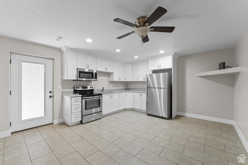 Kitchen with a sink, light countertops, stainless steel appliances, baseboards, and a ceiling fan