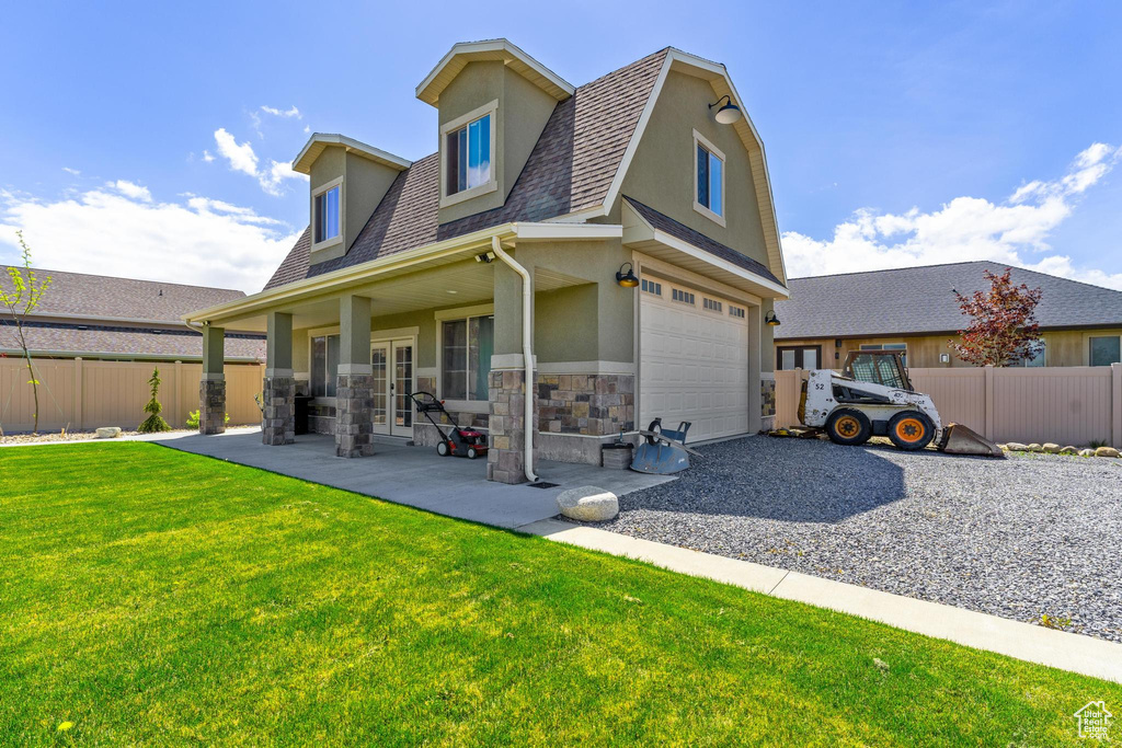 Back of property with a lawn, roof with shingles, fence, and stone siding