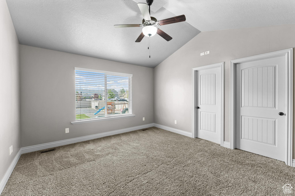 Unfurnished bedroom with baseboards, carpet, vaulted ceiling, and a textured ceiling