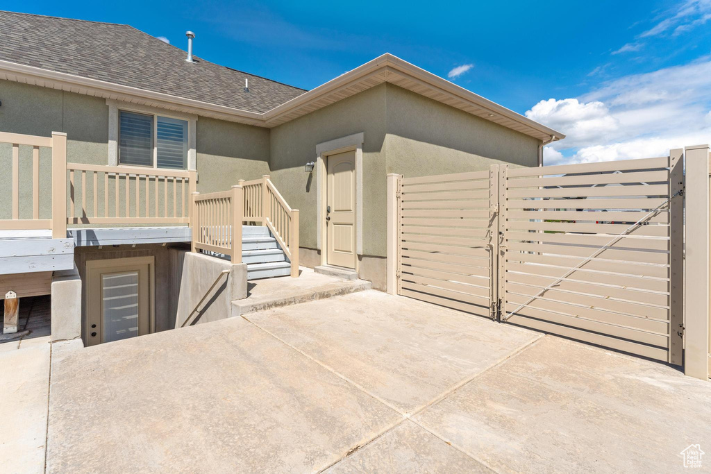 Exterior space featuring stairway, a shingled roof, a gate, and stucco siding