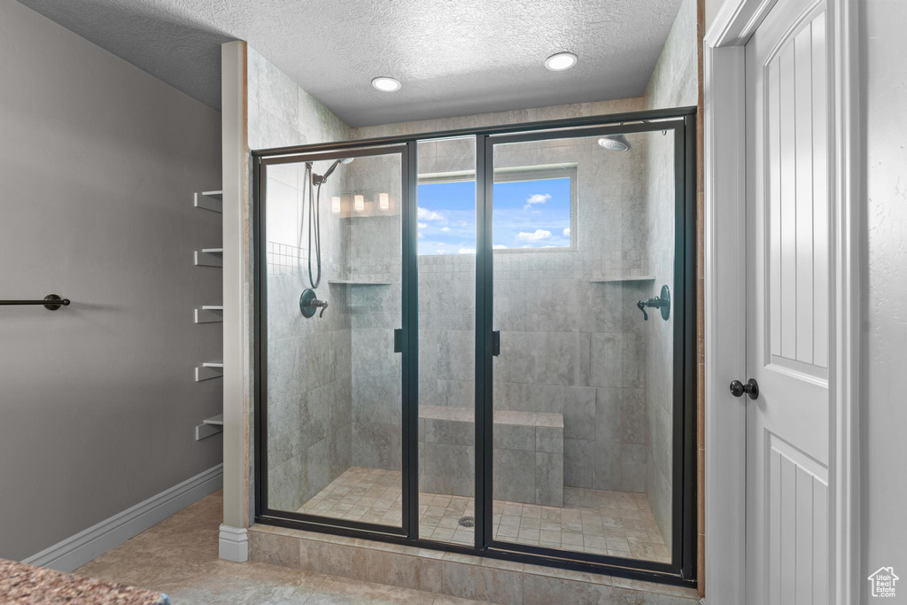 Bathroom with baseboards, a textured ceiling, and a stall shower