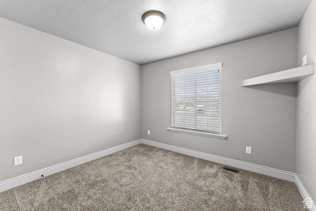 Unfurnished room with carpet floors, a textured ceiling, baseboards, and visible vents