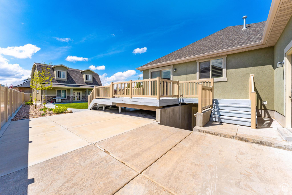 Exterior space with a patio, roof with shingles, fence, and a deck