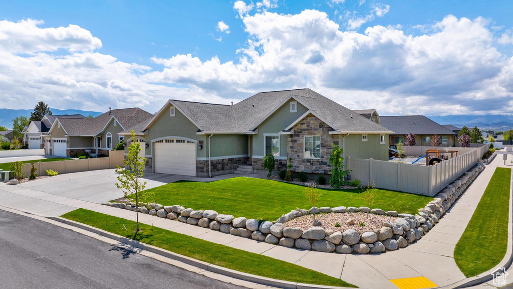 View of front of home with concrete driveway, fence, a residential view, and stone siding