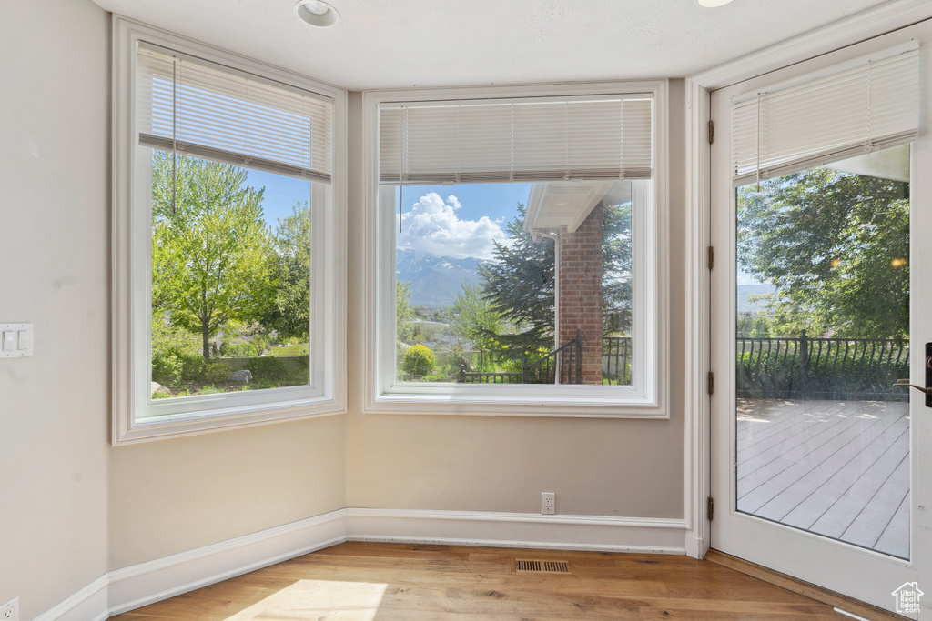 Doorway to outside with baseboards, visible vents, a wealth of natural light, and wood finished floors