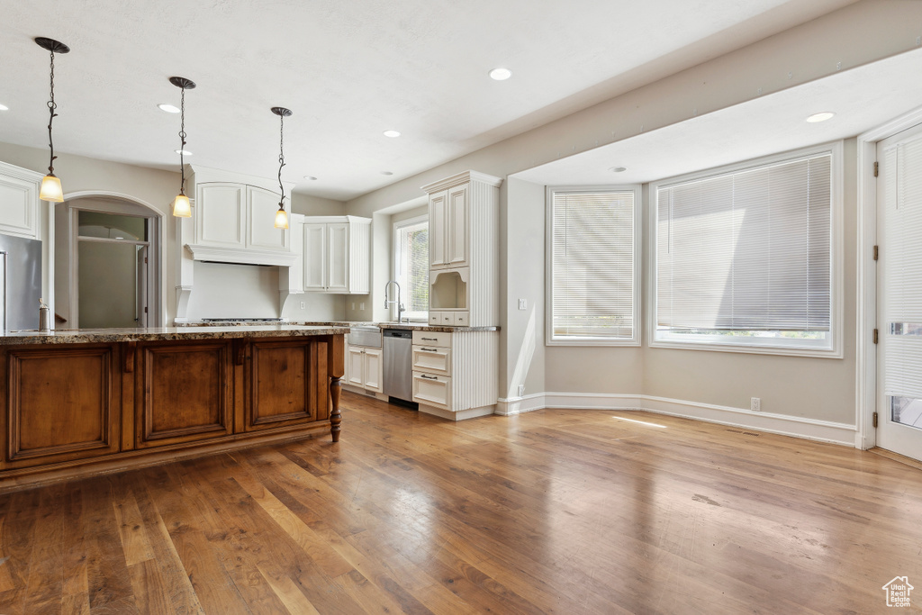 Kitchen featuring stainless steel appliances, baseboards, light stone counters, and wood finished floors