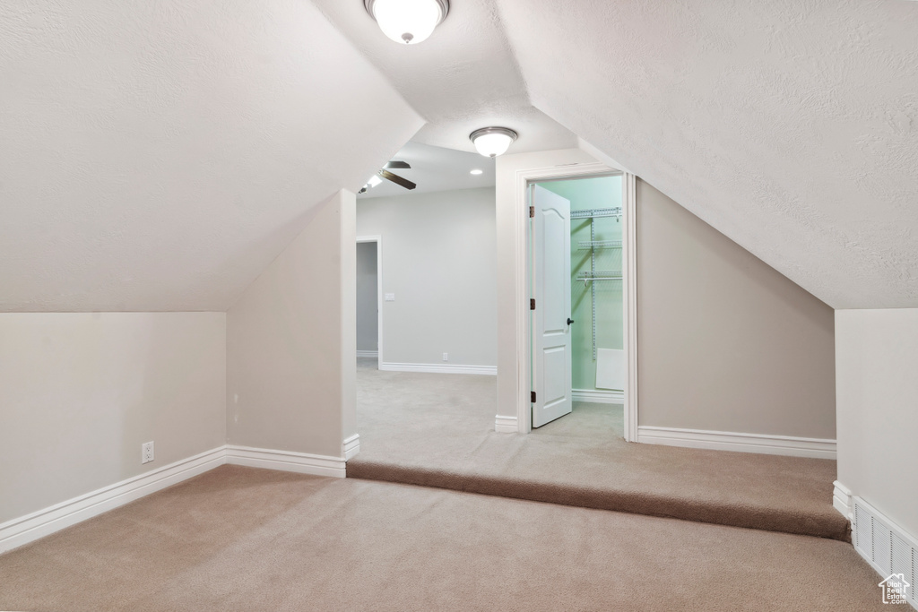 Additional living space featuring visible vents, lofted ceiling, baseboards, a textured ceiling, and carpet