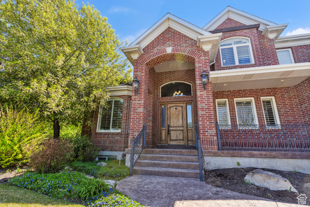 Doorway to property with brick siding and covered porch