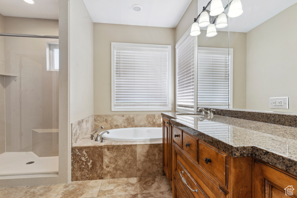 Full bath with an inviting chandelier, a shower stall, a bath, and vanity