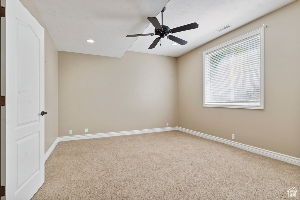 Empty room featuring carpet floors, a ceiling fan, baseboards, and visible vents