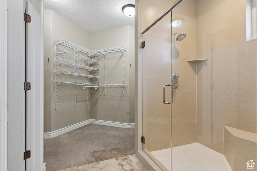 Full bathroom with baseboards, a spacious closet, and a shower stall
