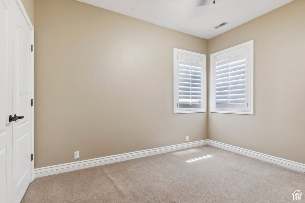 Empty room with carpet floors, baseboards, and visible vents