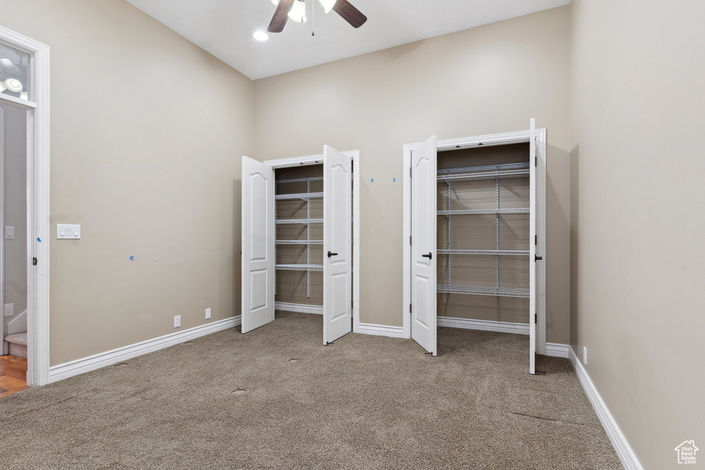 Unfurnished bedroom with ceiling fan, multiple closets, baseboards, and carpet floors