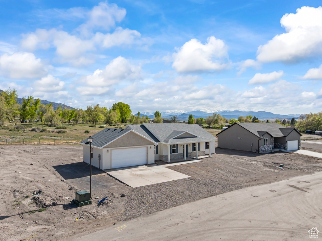 Ranch-style home with concrete driveway, an attached garage, covered porch, and a mountain view