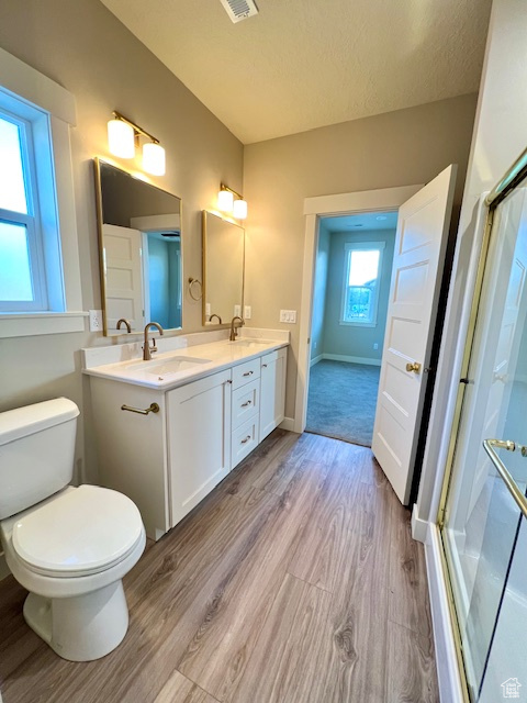 Full bath featuring wood finished floors, an enclosed shower, double vanity, toilet, and baseboards