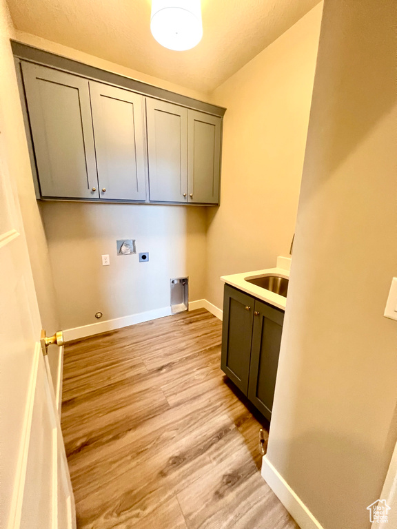 Laundry area with baseboards, hookup for a washing machine, light wood-style flooring, cabinet space, and hookup for an electric dryer