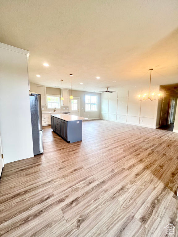 Kitchen with light wood-style floors, freestanding refrigerator, recessed lighting, and open floor plan