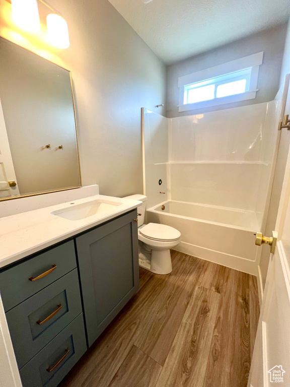Full bathroom with vanity, wood finished floors, toilet, and shower / washtub combination