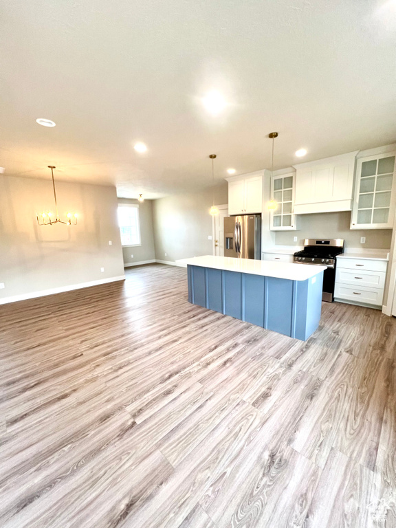 Kitchen with light countertops, light wood-style flooring, a center island, stainless steel appliances, and white cabinetry