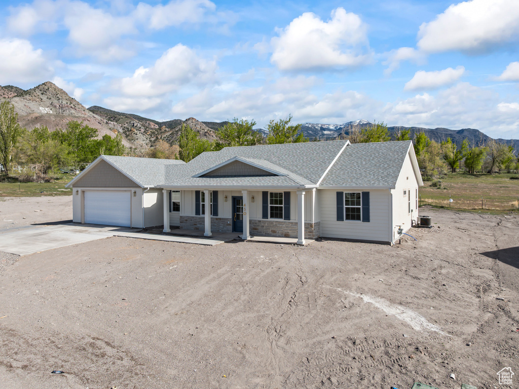 Ranch-style home with covered porch, a garage, a mountain view, concrete driveway, and stone siding