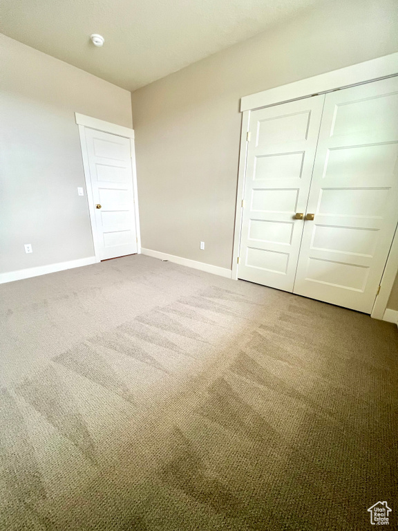 Unfurnished bedroom with baseboards, carpet flooring, and a closet