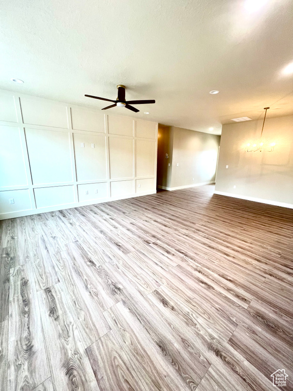 Interior space featuring ceiling fan, a textured ceiling, baseboards, and wood finished floors