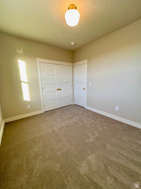 Unfurnished bedroom featuring baseboards, carpet flooring, and a closet