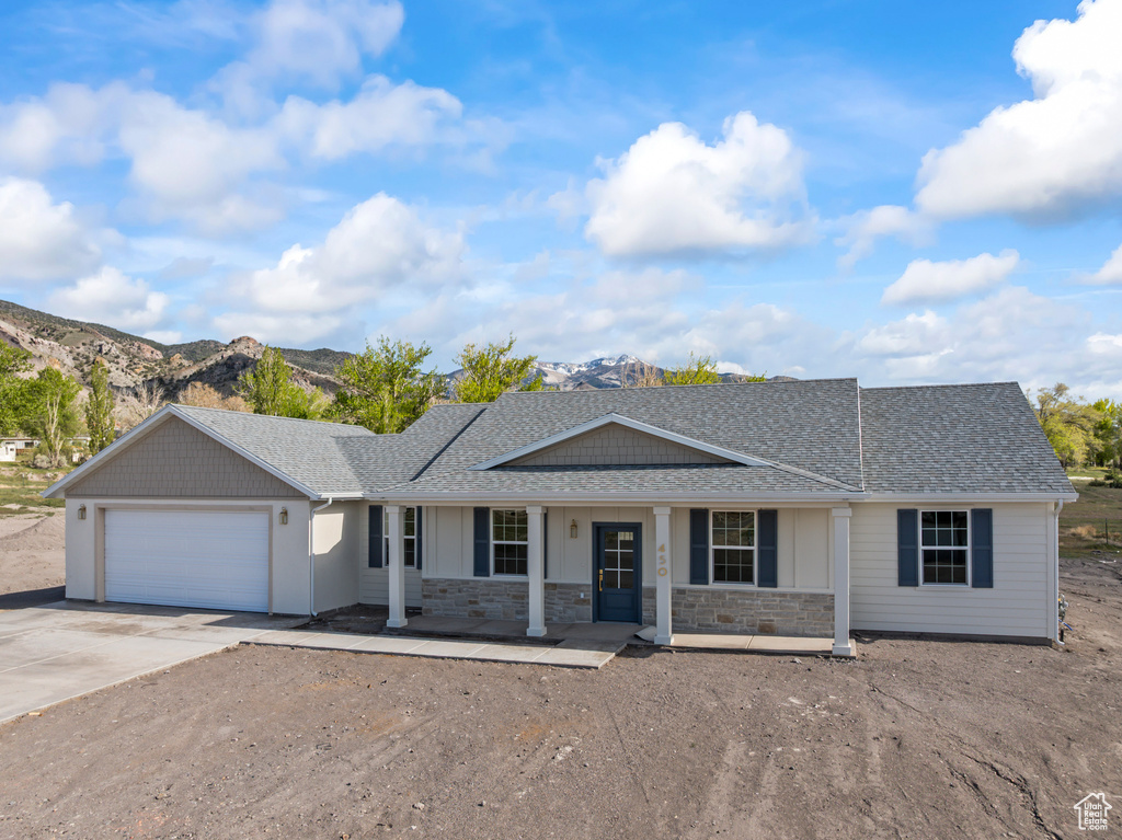 Single story home featuring covered porch, a shingled roof, an attached garage, a mountain view, and driveway