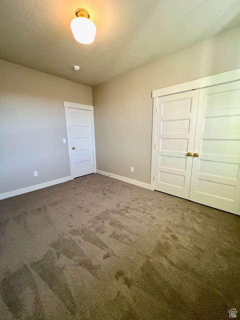 Unfurnished bedroom featuring carpet, baseboards, a closet, and a textured ceiling