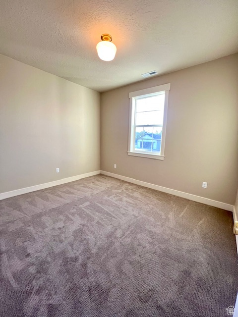 Empty room with carpet flooring, a textured ceiling, and baseboards