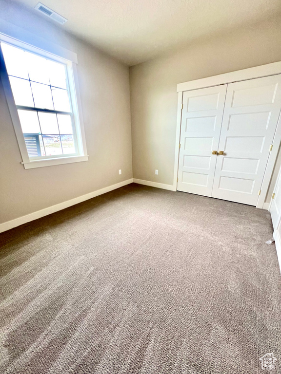 Unfurnished bedroom featuring baseboards and dark carpet