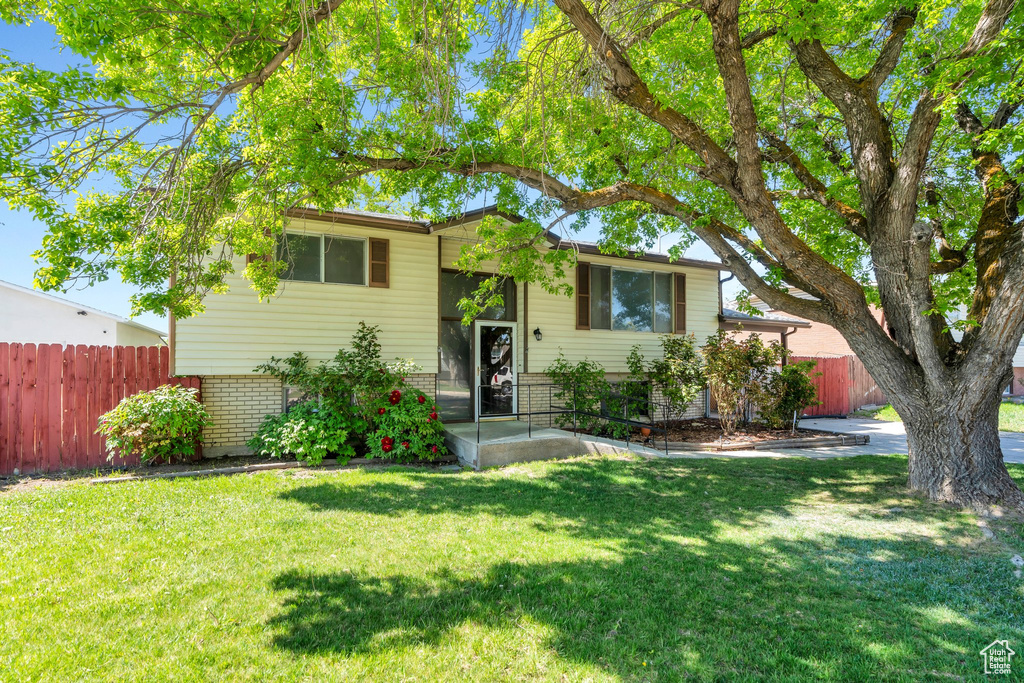 Raised ranch featuring fence, a front lawn, and brick siding