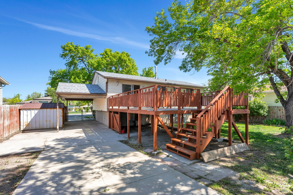 Rear view of house with fence, a wooden deck, a shed, stairs, and driveway