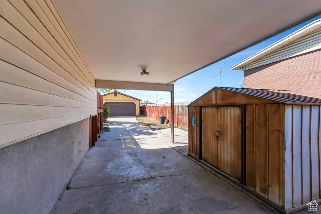 View of patio with driveway, fence, and an outdoor structure
