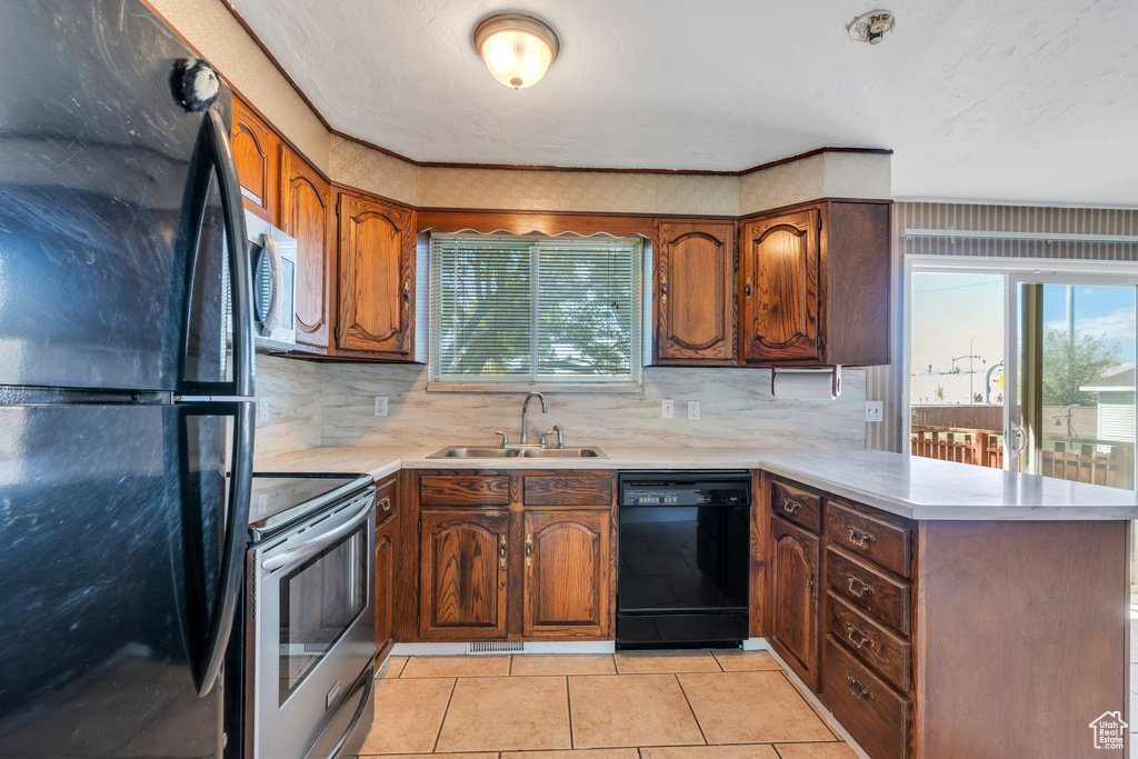 Kitchen featuring a sink, a peninsula, black appliances, and a wealth of natural light