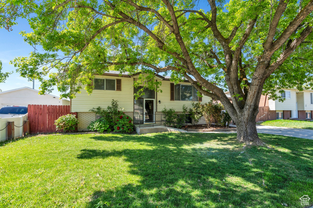 Bi-level home with brick siding, a front lawn, and fence