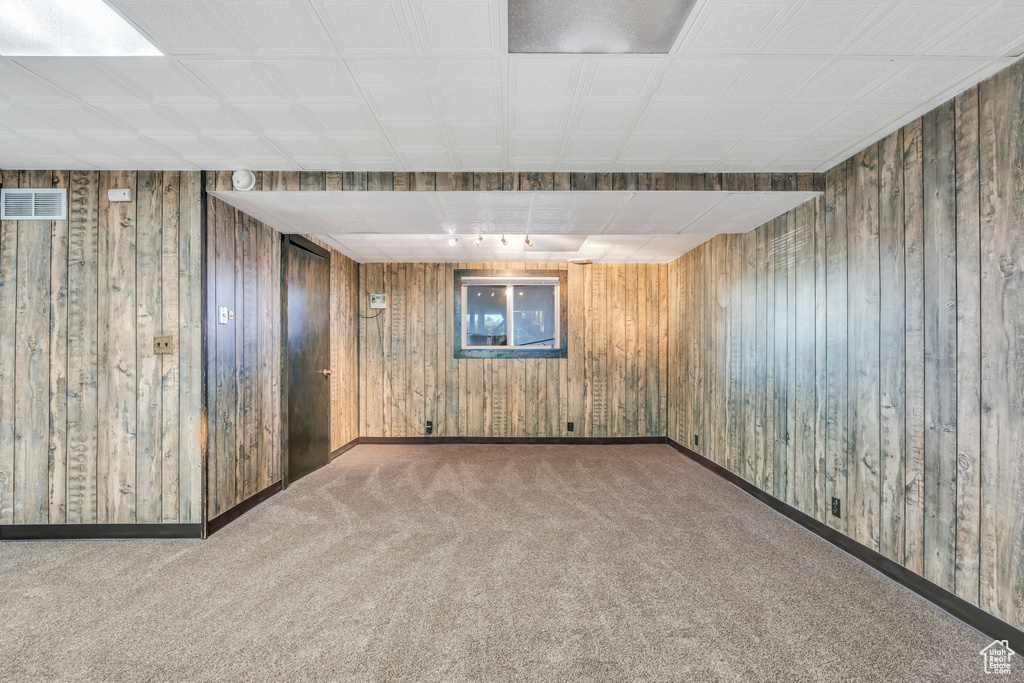 Finished basement featuring carpet floors, wooden walls, baseboards, and visible vents