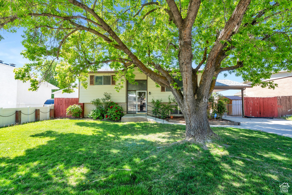 View of front of property featuring brick siding, fence, and a front lawn